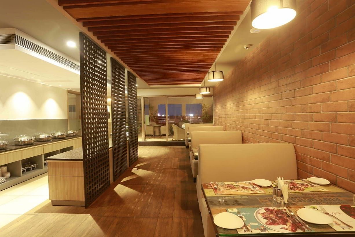 MInt N Musttard Restaurant at Mayberry Tiruppur with sofa chairs and tables arranged with table mat and cutleries